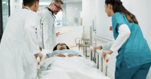 Image of a hospital scene with medical staff surrounding a patient on a stretcher.